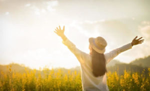 Finding Meaning Therapy - Woman in a field with sun shining above