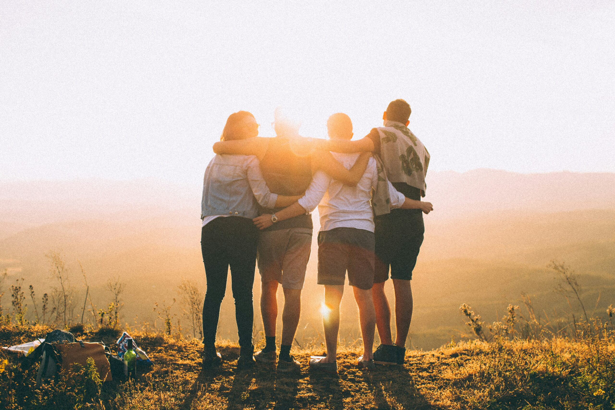 four friends with their backs to the camera looking at the sunset